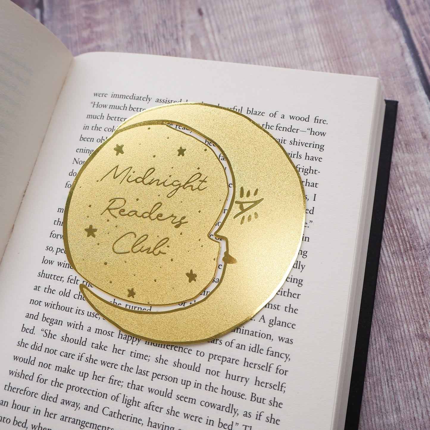 Gold 'Midnight Readers Club' bookmark on an open book