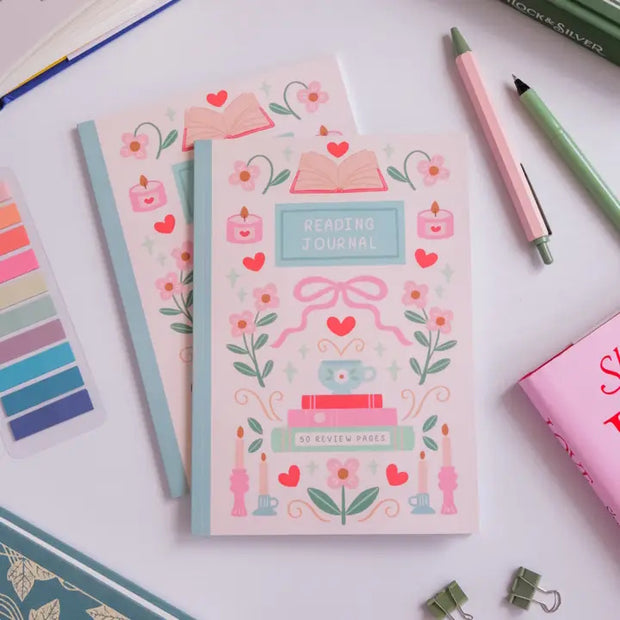 Decorative notebooks with illustrations on a white surface with stationery items.