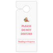 A white door hanger with a hole at the top, featuring a small illustration of a child reading books and the text 'PLEASE DO NOT DISTURB' and 'Reading in Progress' in pink on a white background.