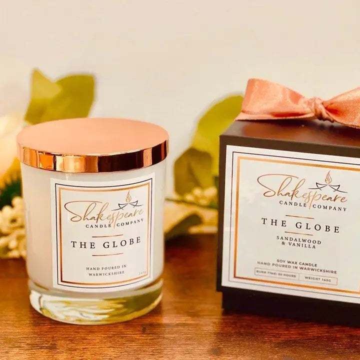 Shakespeare Candle Company candle and packaging on a wooden surface with leaves in the background