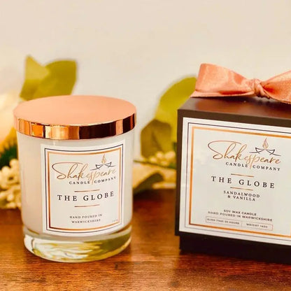 Shakespeare Candle Company candle and packaging on a wooden surface with leaves in the background