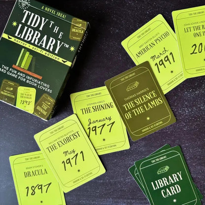Card game packaging and cards titled 'Tidy the Library' on a dark surface